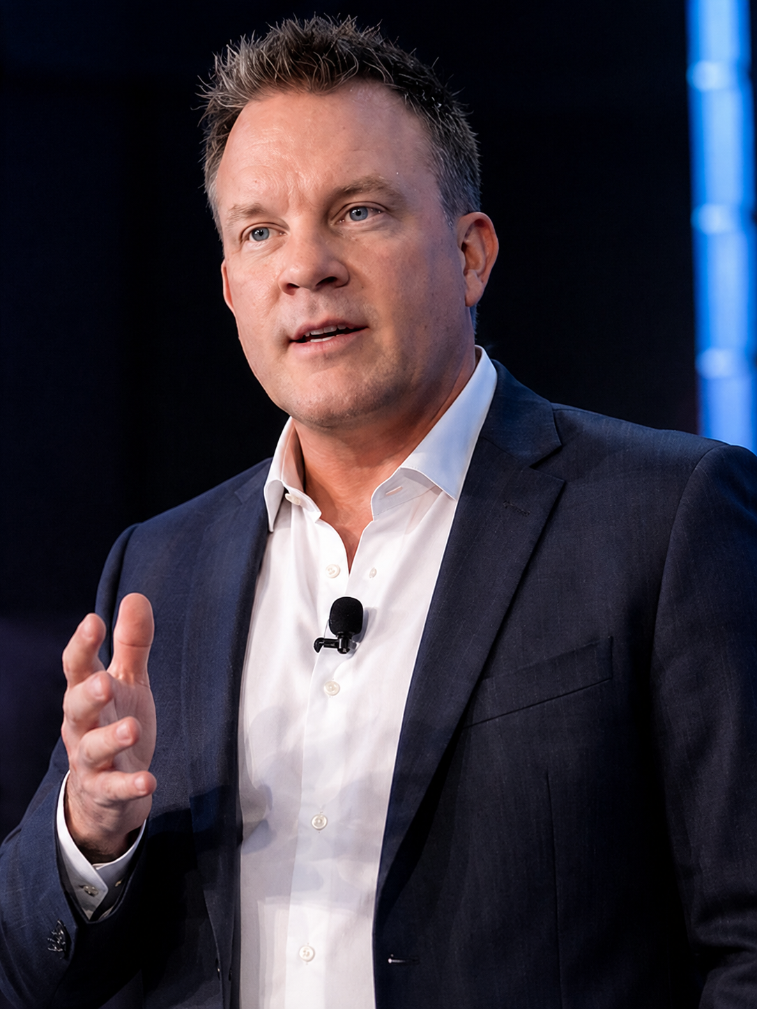 Anthony G. Beck presenting on stage with a lapel microphone